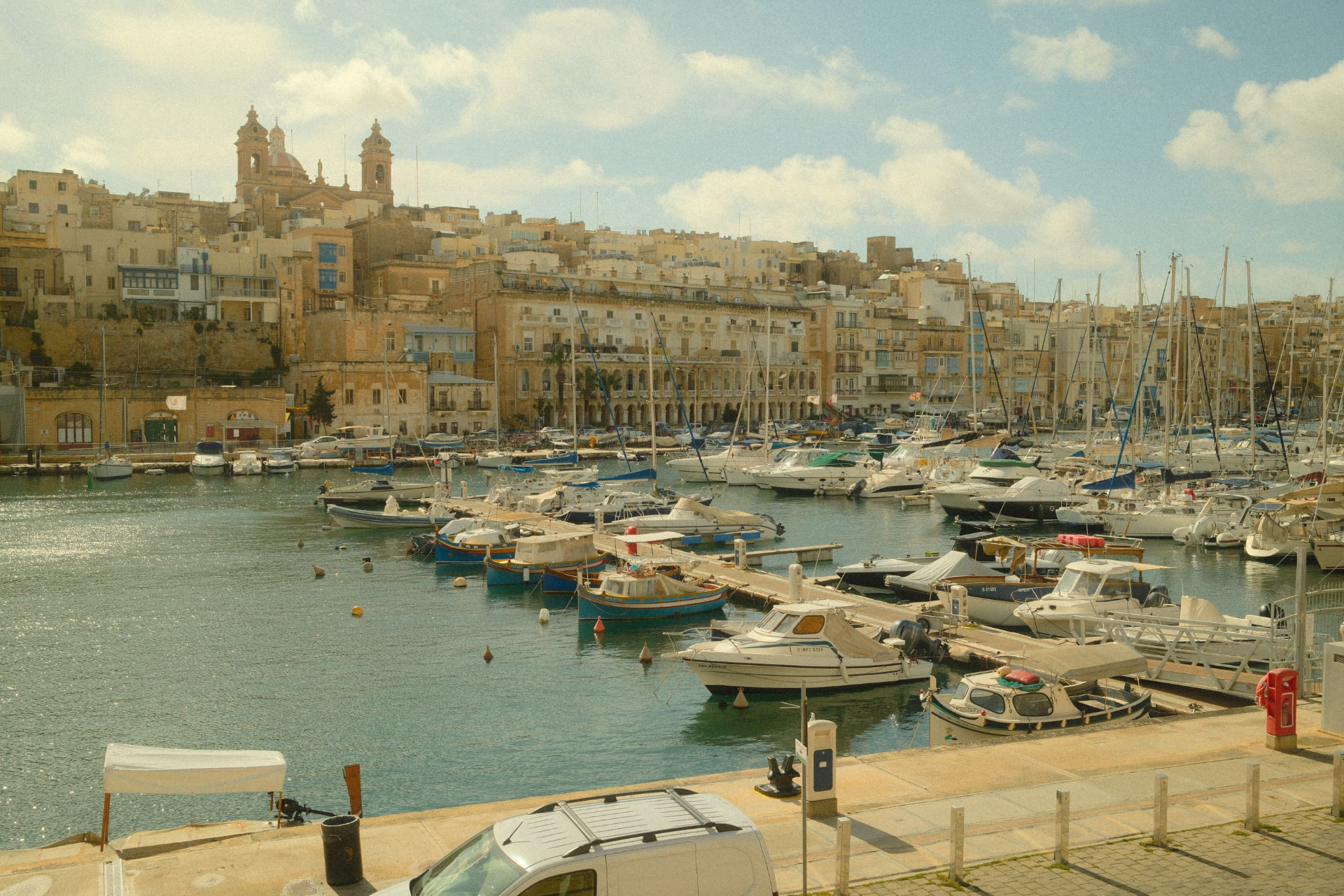 Sunny marina along the Valletta waterfront, with boats and historic buildings
